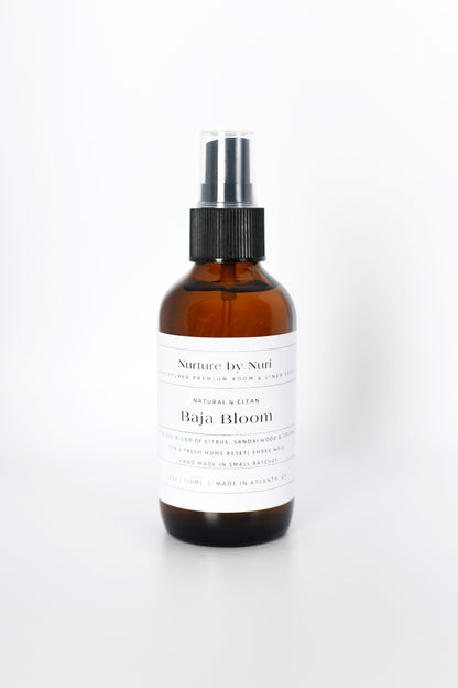 Brown spray bottle labeled 'Nurture by Nuri Baja Bloom' on a white background. Room and linen Spray